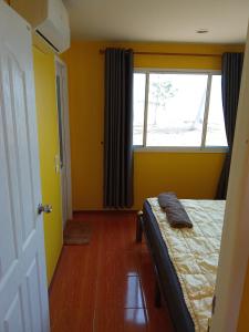 Ban Hin Sam KonHomeState Bang Maprao的一间卧室设有黄色的墙壁和一张带窗户的床
