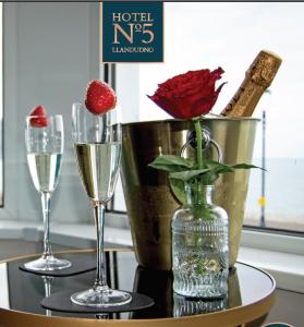 兰迪德诺Hotel No5的一张桌子,上面放着两杯香槟和花瓶里的玫瑰