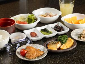 弘前市Tabist Hirosaki Touei Hotel的餐桌,盘子上放着食物和碗