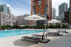 香港悦来酒店的大楼旁的游泳池配有遮阳伞和躺椅