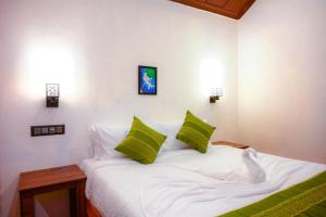 马迪凯里Coorg Mystere - Luxury Homestay的卧室配有带绿色枕头的白色床