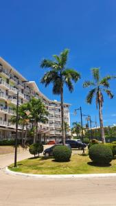 麦克坦Zhamira Avior's Condominium的棕榈树停车场和大楼