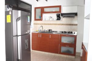 麦德林Medellin My Home的厨房配有木制橱柜和不锈钢冰箱。