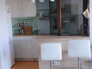 奥卡尼亚Rincón de Relax的厨房配有白色橱柜和2把白色椅子
