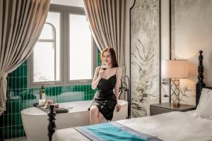 头顿T-Maison Indochine Vung Tau Villa near beach with pool, billiards, karaoke的坐在酒店房间的浴缸里的女人