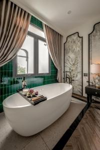 头顿T-Maison Indochine Vung Tau Villa near beach FREE pool, billiards, karaoke的浴室设有绿色瓷砖,配有大型白色浴缸。