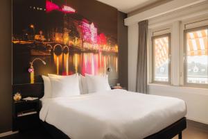 阿姆斯特丹阿姆斯特丹马诺尔酒店的卧室配有一张白色大床,墙上挂有绘画作品