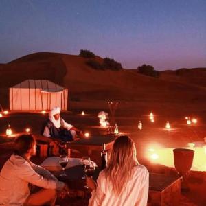 梅尔祖卡Desert Luxury Camp Experience的一群人坐在沙漠的桌子旁
