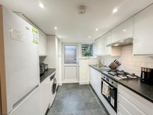 伦敦Charming apartment with a small garden in Finsbury Park的厨房配有白色橱柜和炉灶烤箱。