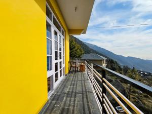 麦罗肯机Young Monk Hostel & Cafe Dharamkot的黄色房屋 - 带景观阳台