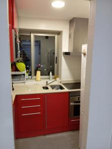 马盖鲁夫Villa Juanmi的厨房配有红色橱柜和炉灶烤箱