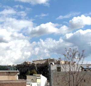 雅典AIONION RESIDENCES by K&K的天空中云层的山丘上的建筑