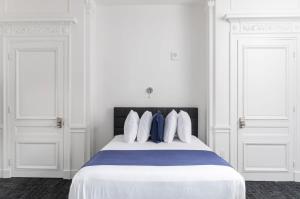 波士顿Stylish Studio in Historic Boston - Unit #204的白色卧室配有一张带蓝色枕头的大床