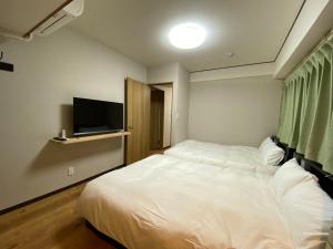 东京浅草・花豆HOTEL的卧室配有白色的床和平面电视。