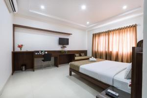 班加罗尔Sanctum Suites BEL Road Bangalore的一间卧室配有一张床、一张书桌和一台电视