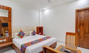 勒克瑙FabExpress Pravi Inn的一间卧室配有一张床、一张桌子和一面镜子