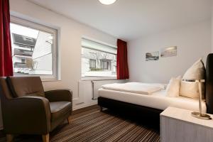 黑尔戈兰岛Hotel Felsen-Eck的卧室配有床、椅子和窗户。