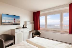 黑尔戈兰岛Hotel Felsen-Eck的酒店客房设有一张床和一个带灯塔的窗户