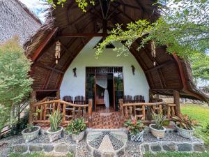 TimbanglawangSumatra Orangutan Treks Villa的茅草屋顶和椅子的房子