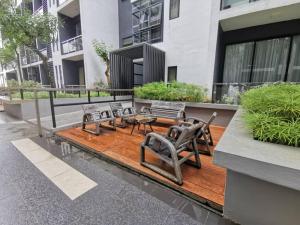 古晋Mupify Homestay Gala City Gala Residences A4的木制甲板上配有桌椅的庭院