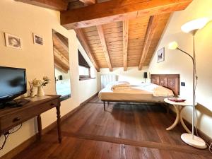 努斯Maison Rosset agriturismo, CAMERE, appartamenti e spa in Valle d'Aosta的一间卧室配有一张床和一张书桌及电视