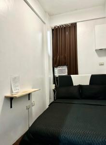 马尼拉Private room with AC and fan at EKG House Rental的一间卧室设有一张黑色的床和一个窗户。