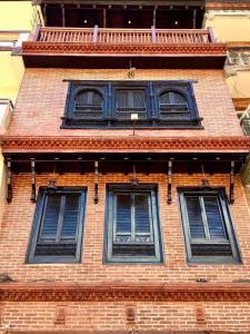帕坦Shahi Studio Apartment的砖楼三扇窗户,设有蓝色百叶窗