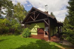 KamińskoKamińsko by Latowisko - Puszcza Zielonka的一座绿色的小建筑,在院子里设有甲板