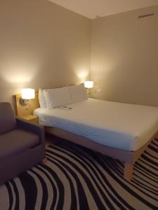 沃尔斯雷诺富特曼切斯特西区酒店的配有一张床和一把椅子的酒店客房