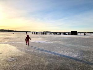 坦佩雷Upea kohde Näsijärven rannassa的背靠码头在海滩上行走的人