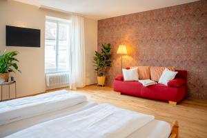 穆尔海姆Biohotel Alte Post的一间卧室设有红色的沙发和窗户。