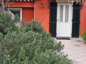 因佩里亚Tenuta Agriturismo IL RISVEGLIO的一间红色的房子,有一扇白色的门和一些灌木丛