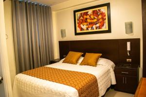 利马Hotel Hatunkay Chaclacayo的卧室配有一张床,墙上挂有绘画作品