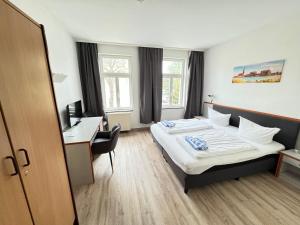 罗斯托克Appartement-Hotel Rostock的配有一张床和一张书桌的酒店客房