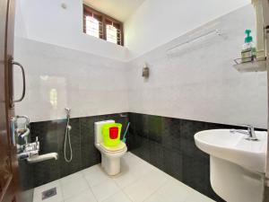 瓦尔卡拉芒果别墅旅馆的浴室设有卫生间,上面有绿色和红色的桶