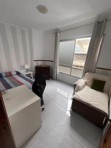 大加那利岛拉斯帕尔马斯Apartamento céntrico y luminoso ALCARAVANERAS的一间卧室配有一张床、一张书桌和一个窗户。
