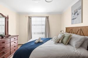 悉尼Beautiful Home In Milperra Sleeps 8的一间卧室配有一张带枕头和梳妆台的大床。