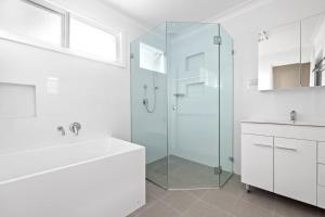 悉尼Beautiful Home In Milperra Sleeps 8的带淋浴和盥洗盆的白色浴室
