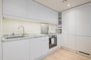 剑桥Luxury City Centre Apartment的白色的厨房配有白色橱柜和水槽
