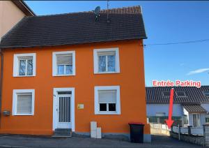 圣路易Suite 2 lits Auberge du Manala Hôtel 24 24 proche Basel的橙色的房子,红色的箭头指向橙色的屋顶