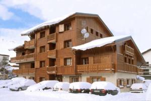 莱德萨阿尔卑斯Alpina Lodge - 02 - Appart rdc duplex - 8 pers的一座大建筑,里面装有汽车停在雪上