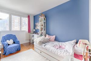 皮托Residor - Warm appartement near Paris的卧室拥有蓝色的墙壁,配有一张床和椅子
