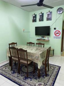 GemenchehAziz homestay的一间带桌椅和电视的用餐室