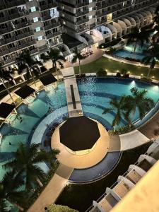 马尼拉Shell Residences by Amonbrey Suite nr airport的享有棕榈树大型游泳池的顶部景致