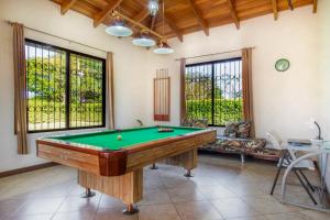 瓜纳卡斯特Villa Roble Alto的客厅设有一张台球桌,客厅设有窗户。