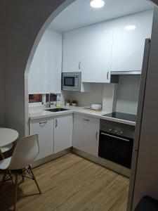 圣波拉Apartamento Caravaca的厨房配有白色橱柜、桌子和椅子
