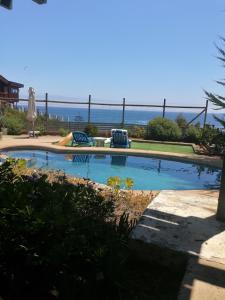 埃尔基斯科CasaMar ElQuisco的一个带两把椅子的游泳池,背景是大海