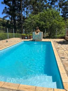 阿尤鲁奥卡Hospedagem Florenza的蓝色的游泳池,旁边有人坐在椅子上