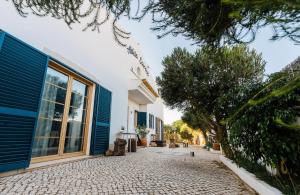 萨格里什Aldeia Caiçara Surf House的一座带蓝色门和石头车道的房子