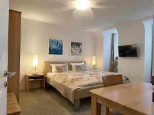 比特堡Zum Simonbräu的一间卧室配有一张床、一张桌子和一台电视。